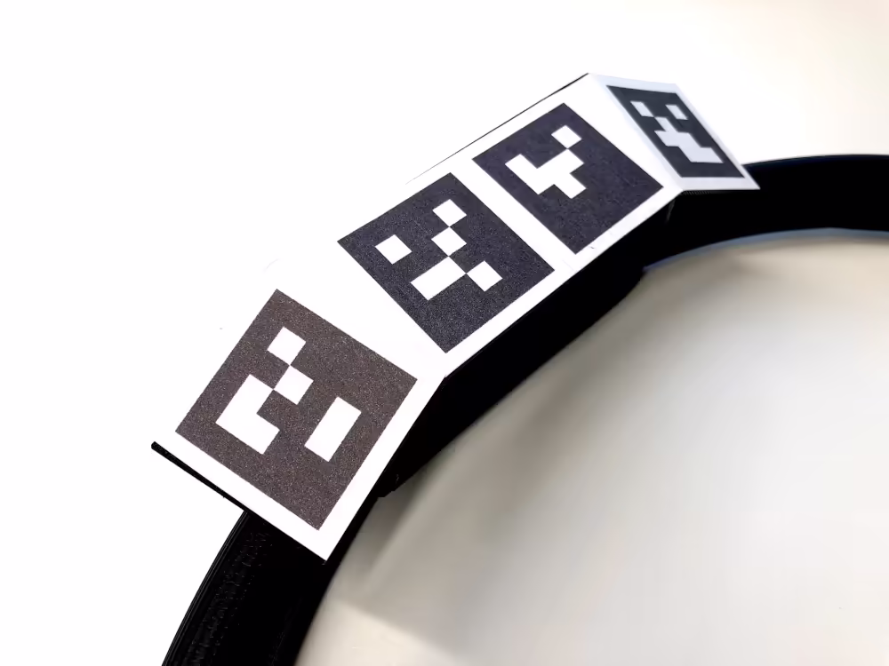 Each ArUco markers has a unique combination of black and white grid squares corresponding to its value surrounded by a solid black border. The markers can be oriented at different angles in 3D space to increase the visibility by the camera. For the ActiveXR device, the marker patterns are printed on paper and attached to a 3d printed structure.